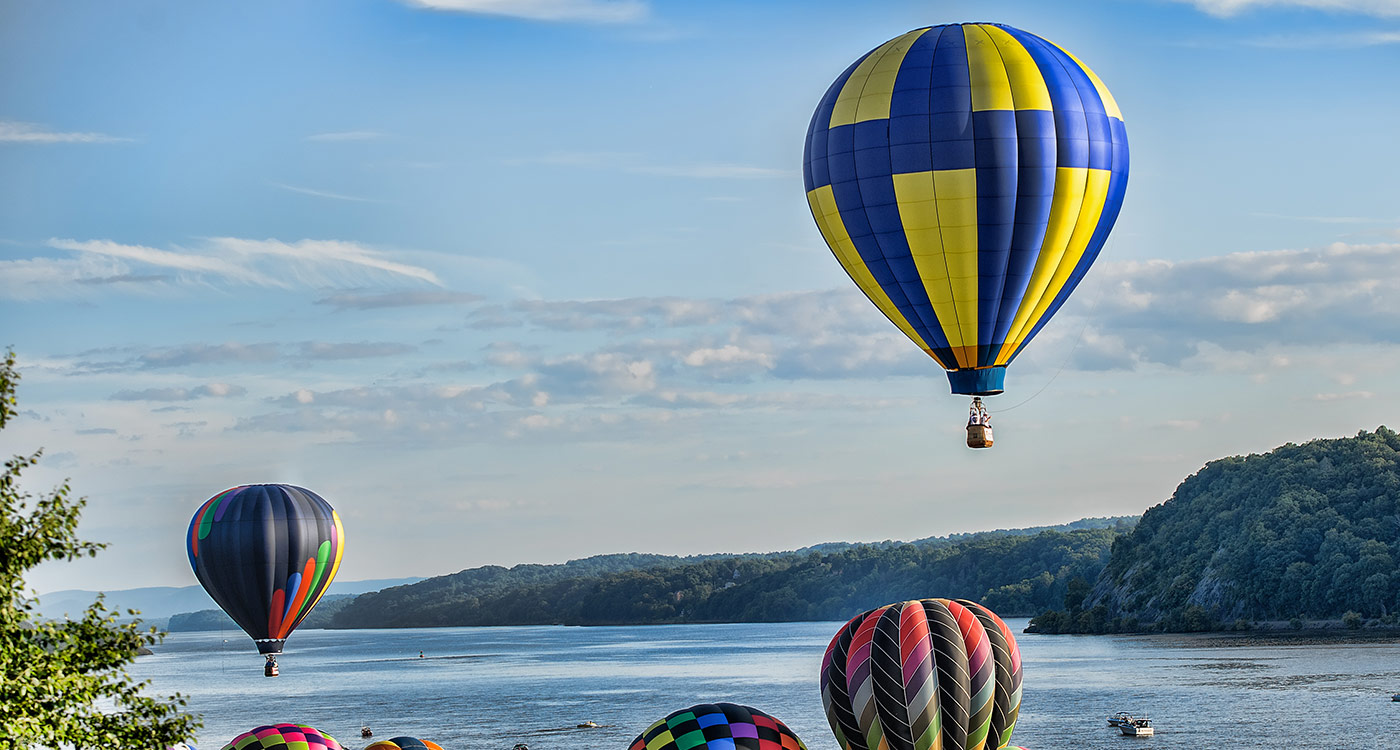 A photo of hot air balloons travelling down the Hudson River.